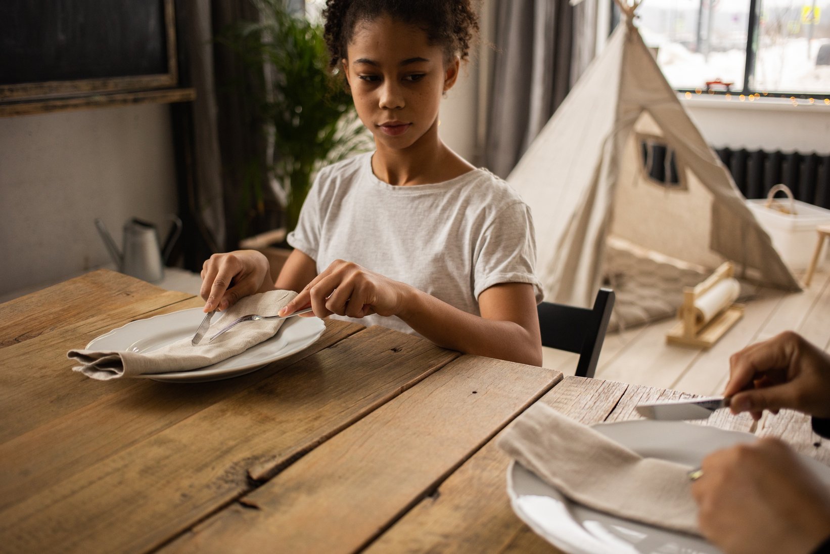 Serious black girl learning table manners